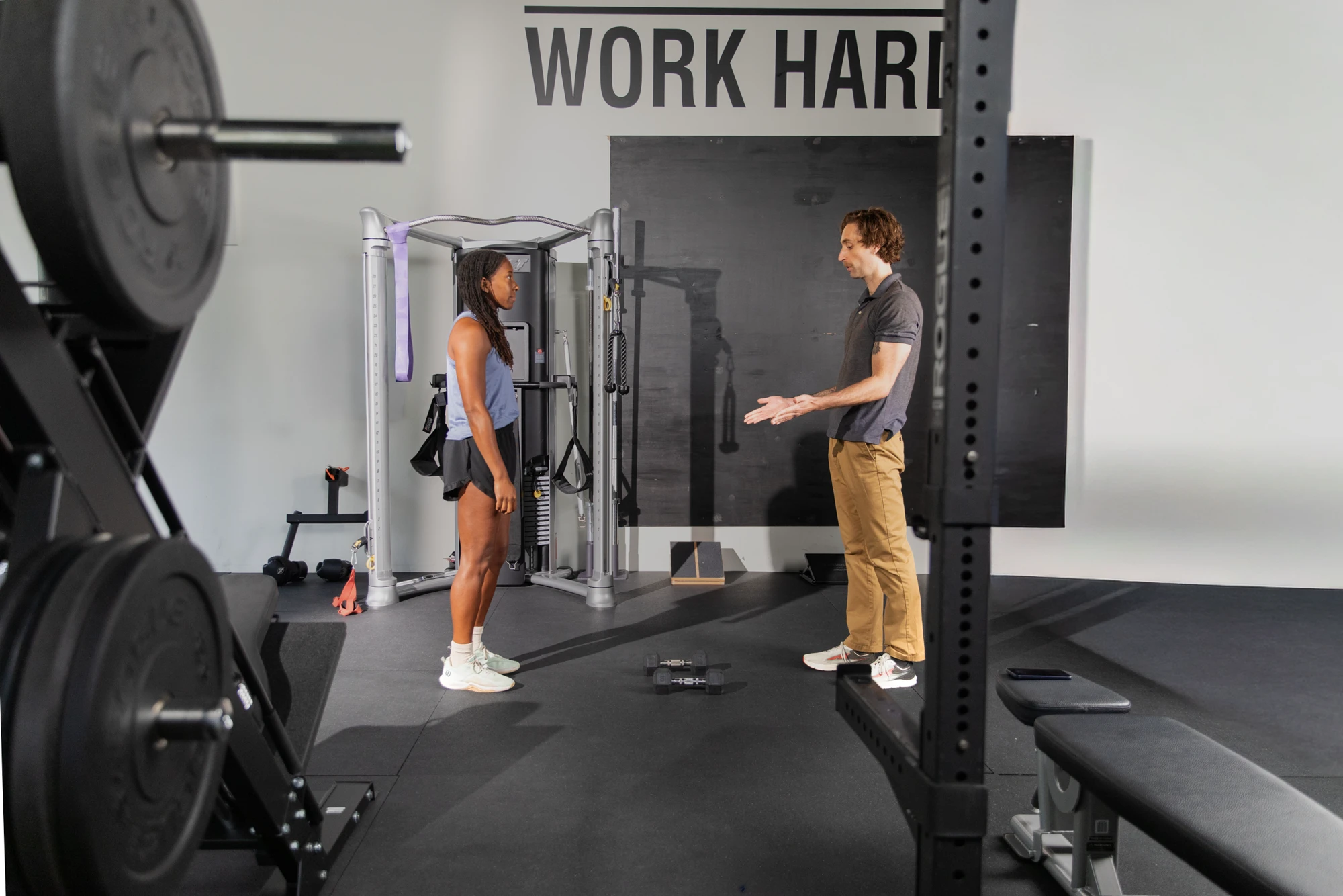 Coach talking an athlete through her session on the gym floor