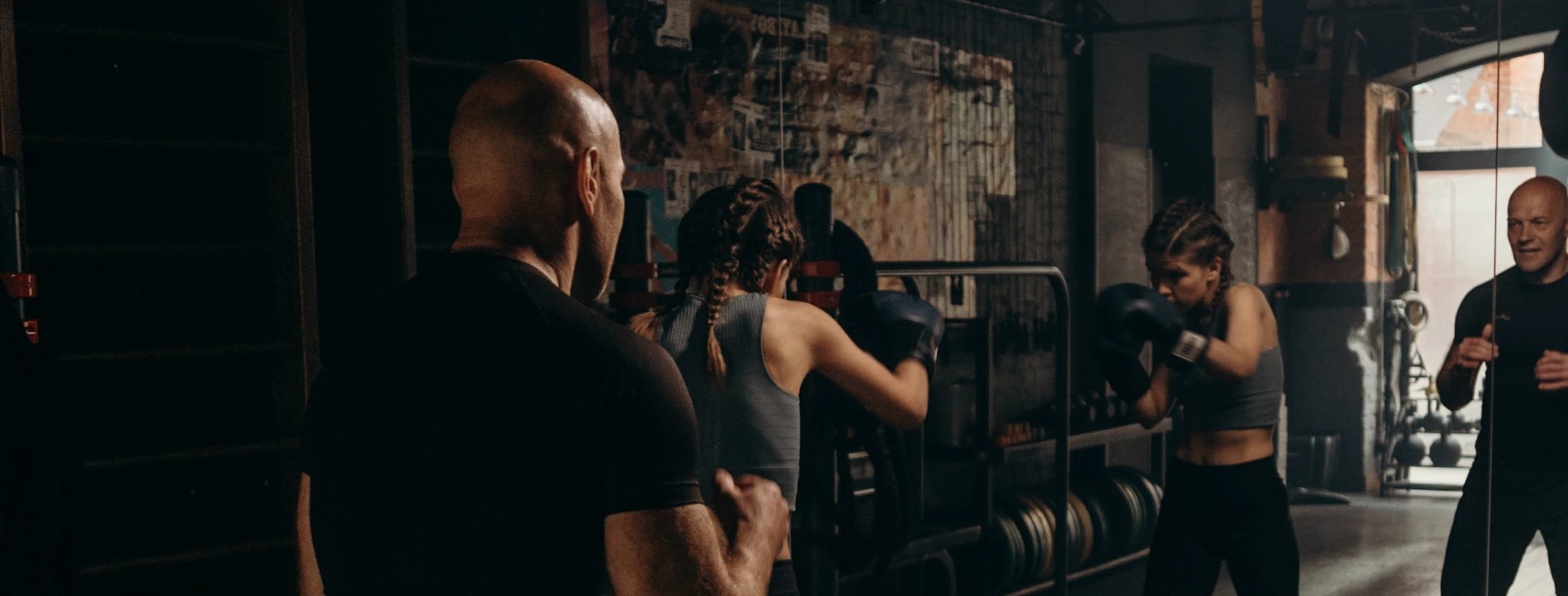 A boxer training with her coach in front of a gym mirror